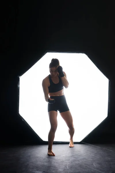 Female boxer training in a dark ring. Slow motion. Silhouette. Boxing concept