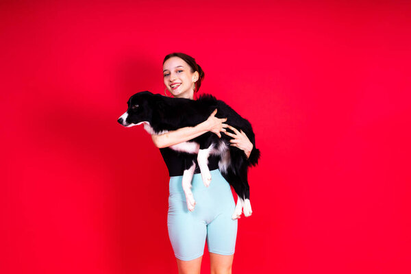 Portrait of female posing with border collie in studio, yellow and red background
