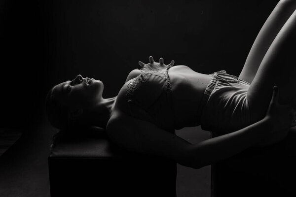 Beautiful female body. Isolated on a dark studio background. Plump woman covering breast.