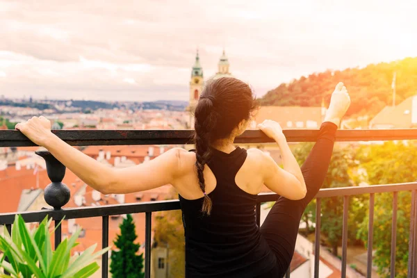 Kadın Prag şehrinin arka planında yoga yapıyor.