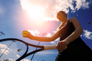 Sahada tenis raketi tutan beyaz elbiseli ve topuklu ayakkabılı seksi kız tenisçi. Genç kadın tenis oynuyor.