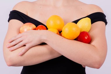 Siyah mayo giymiş, meyvelerle poz veren ve gülen güneş gözlüklü havalı bir kız..