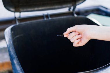 Atık toplama, çöp tenekesine yakın bir kibritle el.