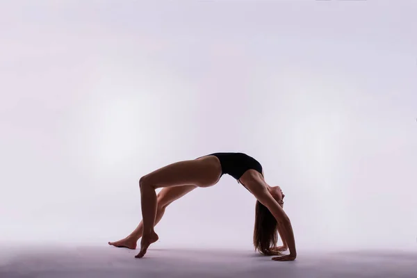 一个漂亮的苗条身材的年轻女子正在锻炼 做瑜伽或普拉提运动的侧视图 — 图库照片