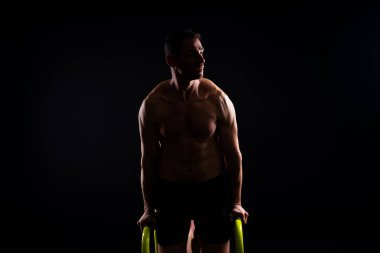 Spor yapan güçlü bir adam. Gorizontal ve paralel parmaklıklar üzerinde zindelik. Paralel çubuklarda yukarı çek.