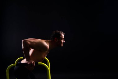 Spor yapan güçlü bir adam. Gorizontal ve paralel parmaklıklar üzerinde zindelik. Paralel çubuklarda yukarı çek.