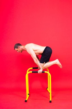 Spor yapan güçlü bir adam. Gorizontal ve paralel parmaklıklar üzerinde zindelik. Paralel çubuklarda yukarı çek.