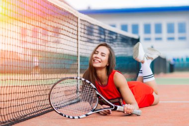 Güzel bayan tenis oyuncusu tenis kortunda kırmızı elbiseli.
