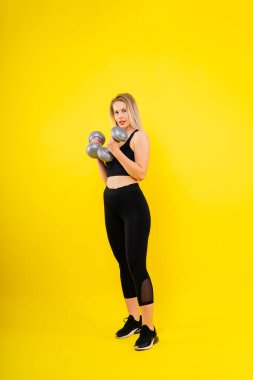 Dambıllarla spor yapan mükemmel bir bayan. Spor giyimli kadın fotoğrafı, stüdyo fotoğrafı.