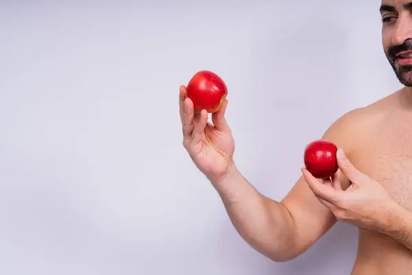 Man, hands and holding apple on white background in a studio for health, wellness or immune support.