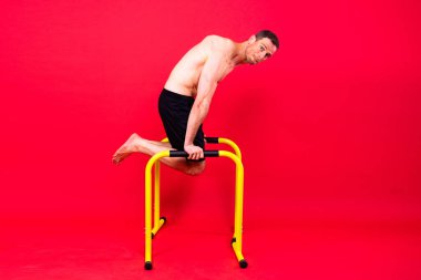 Stüdyoda paralel barlarda egzersiz yapan güçlü bir gencin ön ve yan görüntüsü..