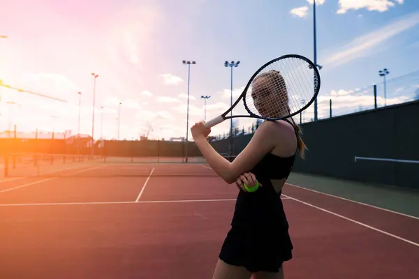 Sensual woman with tennis racket at net on lawn. Activity, energy, power. Sport training workout.