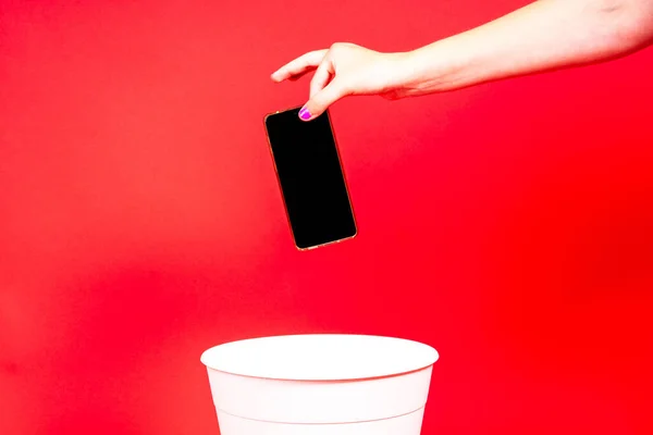 The smartphone is thrown into a trash for disposal and recycling