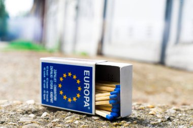 Bir kibrit, şehirdeki eski garajların arka planıyla eşleşen bir el..