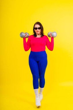 Dambılı, kıvrımlı bir vücudu olan sportif bir model. Dinamik hareket. Motivasyon ve sağlıklı yaşam tarzı