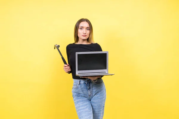 Laptop Repair. Female with hammer and laptop on a yellow background