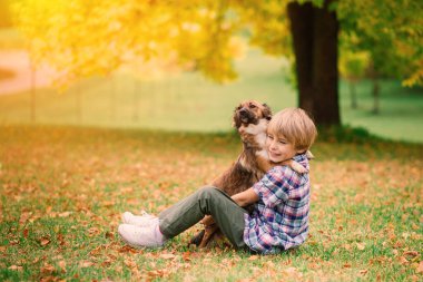 Tatlı çocuk çayırda köpeğiyle oynuyor ve yürüyor..