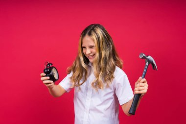 Kid girl holding hammer and alarm clock smiling with happy and cool smile on face. showing teeth.