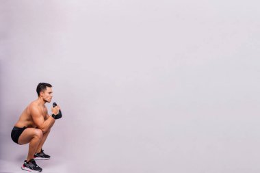 Handsome muscular man holding a kettle bell with copy space. Hispanic male athlete