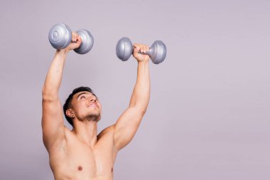 Shirtless bodybuilder showing his great body and holding dumbells.