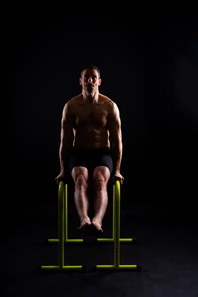 Male gymnast performing handstand on a parallel bars, studio shot
