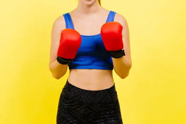 Woman boxer in gloves training on a grey and yellow background