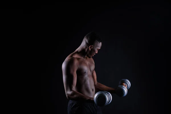 Young man with dumbbells good physique isolated on red black background. Strength and motivation