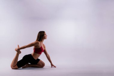 Güzel bir kadın yoga sınıfında Padmasana Lotusu ya da Kamalasana pozu veriyor. Stüdyo çekimi.