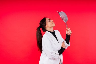 Kırmızı ve beyaz arka planda dişi bir elde un ellemek için metal elek kullanan bir kadın..