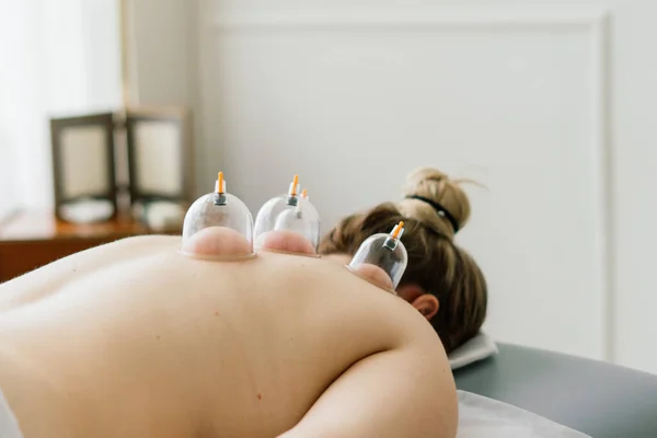 A woman does a hip massage with vacuum jar for an anti-cellulite massage.