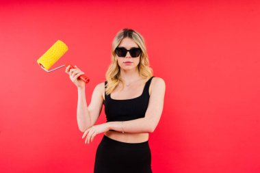 Kırmızı beyaz arka planda paten fırçası olan genç kadın yenileme odası için araç gereç aksesuarları