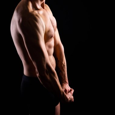 Kaslı, üstsüz, göğüs kaslarını ve karın kaslarını gösteren yakışıklı bir adam.