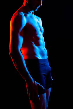 Kaslı, üstsüz, göğüs kaslarını ve karın kaslarını gösteren yakışıklı bir adam.