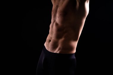 Kaslı, üstsüz, göğüs kaslarını ve karın kaslarını gösteren yakışıklı bir adam.