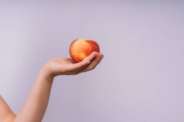 Mutlu genç bir kadının stüdyo portresi, gülümseyen, olgunlaşmış nektarları elinde tutan