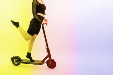 Kırmızı arka planda oturan sarışın bir kadın. Elektro scooter 'da oturuyor ve dinleniyor.