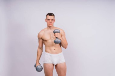 Shirtless bodybuilder holding a dumbell and showing his muscular arms.