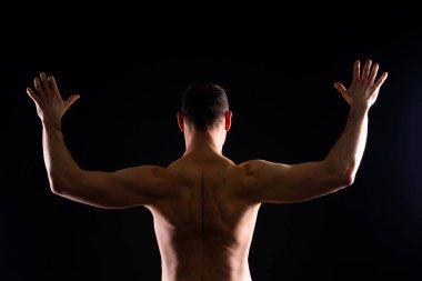 Stüdyoda poz veren kaslı bir adam resmi, koyu beyaz arka plan.