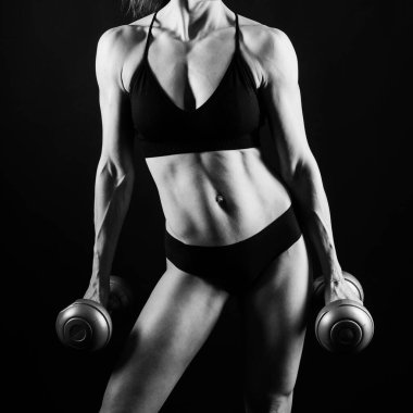 Sportif kadın, dambıllarla egzersiz yapıyor. Silüet stüdyosu koyu sarı arka plan.