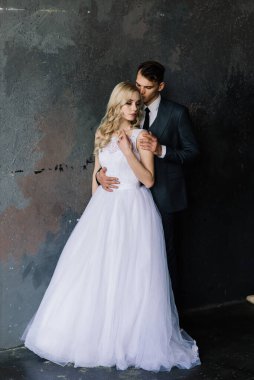 Klasik bir stüdyonun içinde şirin bir düğün çifti. Öpüşüyorlar ve sarılıyorlar..