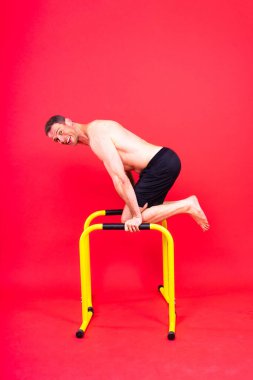 Stüdyoda paralel barlarda egzersiz yapan güçlü bir gencin ön ve yan görüntüsü..