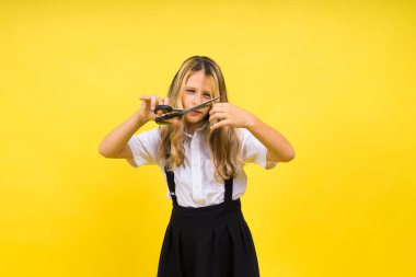 Teenage school girl with scissors, isolated on yellow background. Child creativity, art and crafts.