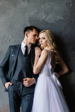 Klasik bir stüdyonun içinde şirin bir düğün çifti. Öpüşüyorlar ve sarılıyorlar..