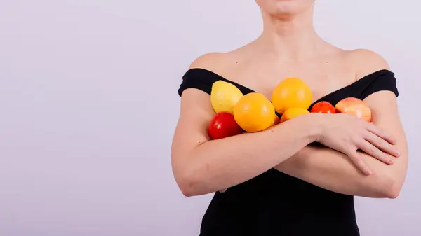 リンゴ レモン オレンジをグレーの背景に隔離されたさまざまな腕に保持する女性 — ストック写真