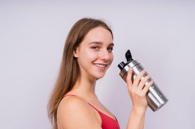 Spor şişesinden tatlı su içen spor düşkünü bir kadının yakından görüntüsü.