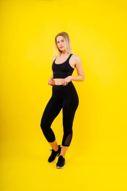 Orta yaşlı kadın spor yapıyor, kasları ve kaslarıyla spor kıyafetinin üzerinde duruyor, mutlu bir şekilde gülümsüyor.