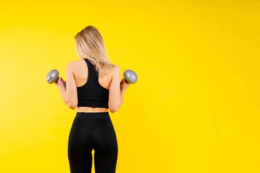 Güçlü kadın dambıllarla çalışıyor, kolunu esnetiyor. Spor kıyafetli bir kadının fotoğrafı..