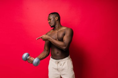 Kırmızı ve siyah arka planda dambılları olan mutlu Afrikalı bir adamın portresi.