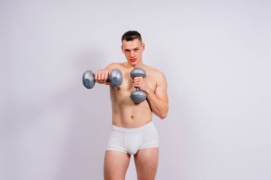 Shirtless bodybuilder holding a dumbell and showing his muscular arms.