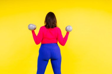 Dambılı, kıvrımlı bir vücudu olan sportif bir model. Dinamik hareket. Motivasyon ve sağlıklı yaşam tarzı